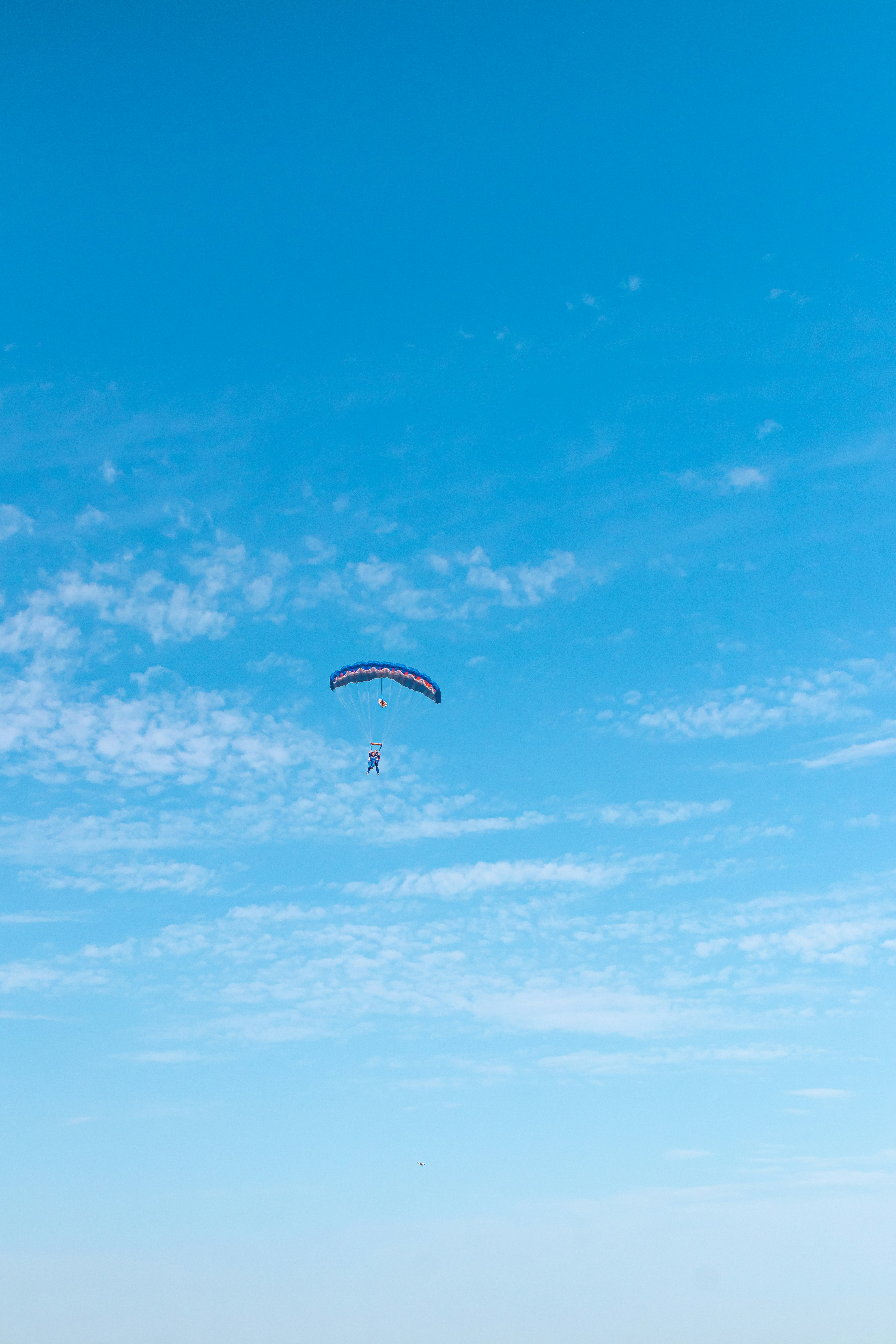 person in parachute under blue sky during daytime